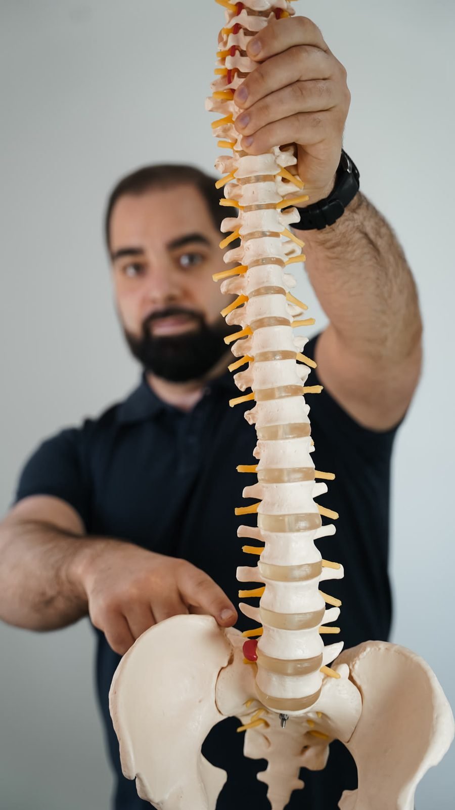 Modelo anatómico da coluna vertebral, segurado por Mário Pereira em primeiro plano.